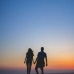 Man and woman holding hands in silhouette photography.
